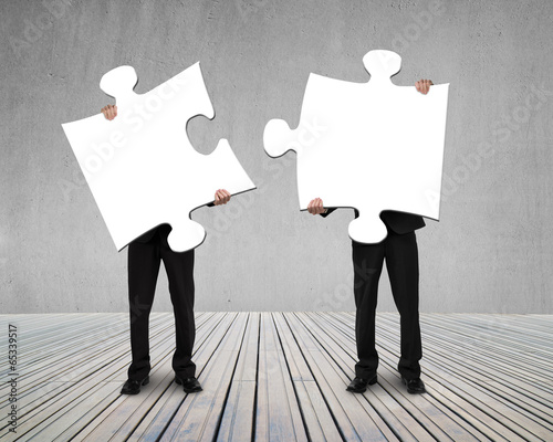 Businessmen holding two puzzles to connect