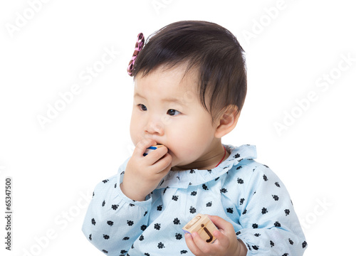 Asia baby girl put wooden toy block into mouth