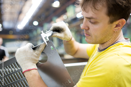 Worker Measuring Detail with Vernier Caliper in Factory Workshop