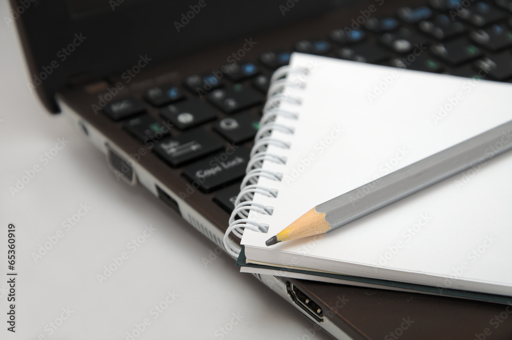 Notebook with pencil on laptop keyboard Notebook with pencil on laptop keyboard