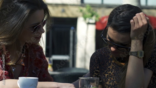 Women consoling her friend in street cafe, steadycam shot photo