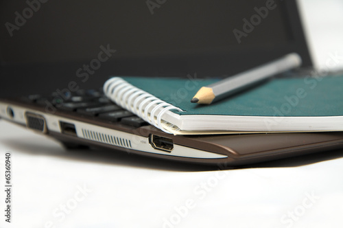 Notebook with pencil on laptop keyboard