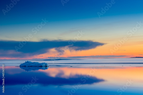 The melting iceberg on spring mountain lake in the setting sun.