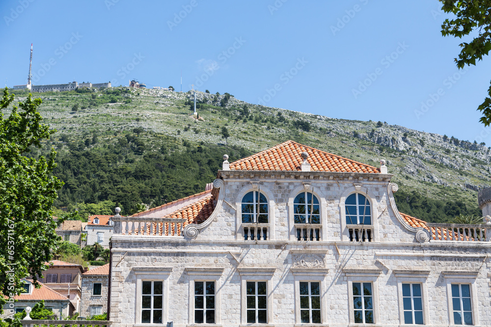 Old Stone Building with Red Tile Roof Under Green Dubrovnik Hill