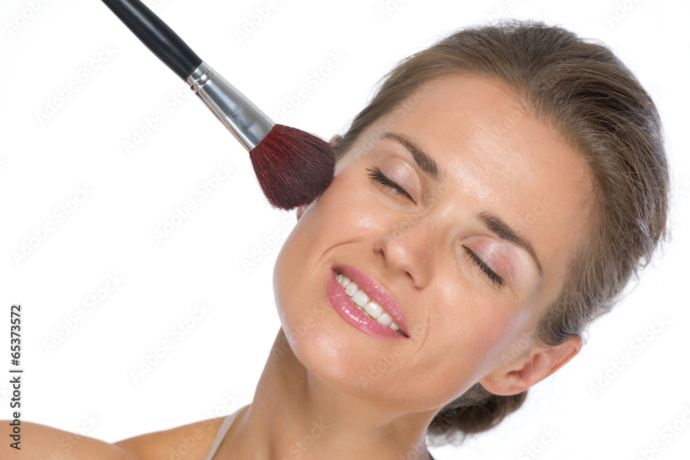 Young woman using makeup brush