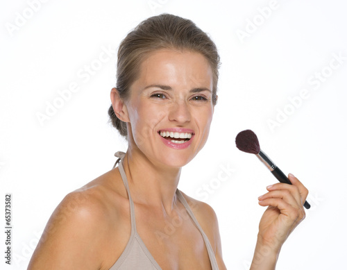 Portrait of happy young woman with makeup brush