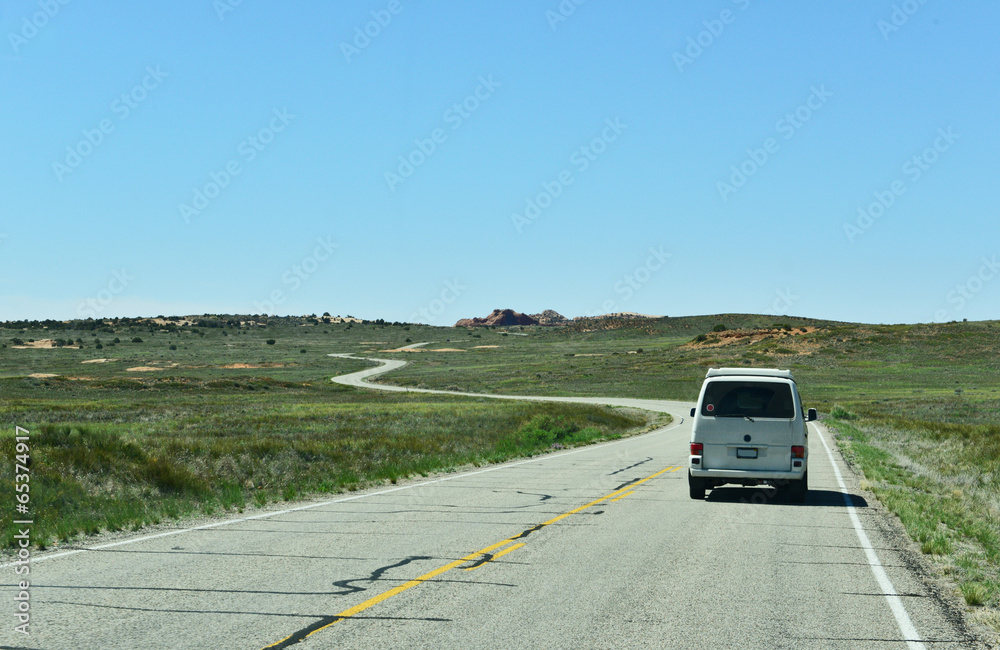 A white RV driving along a road in Canyon Lands, Utah