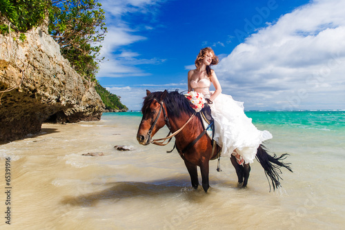 happy bride walking with horse on a tropical beach