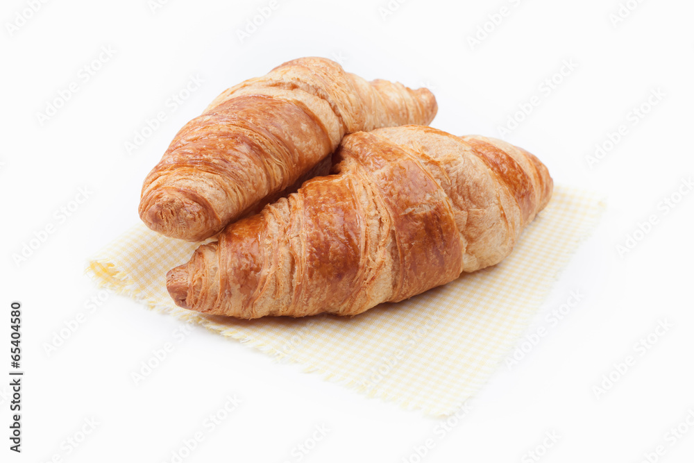 Fresh and tasty croissant on yellow checkered napkin over white Fresh and tasty croissant on yellow checkered napkin over white