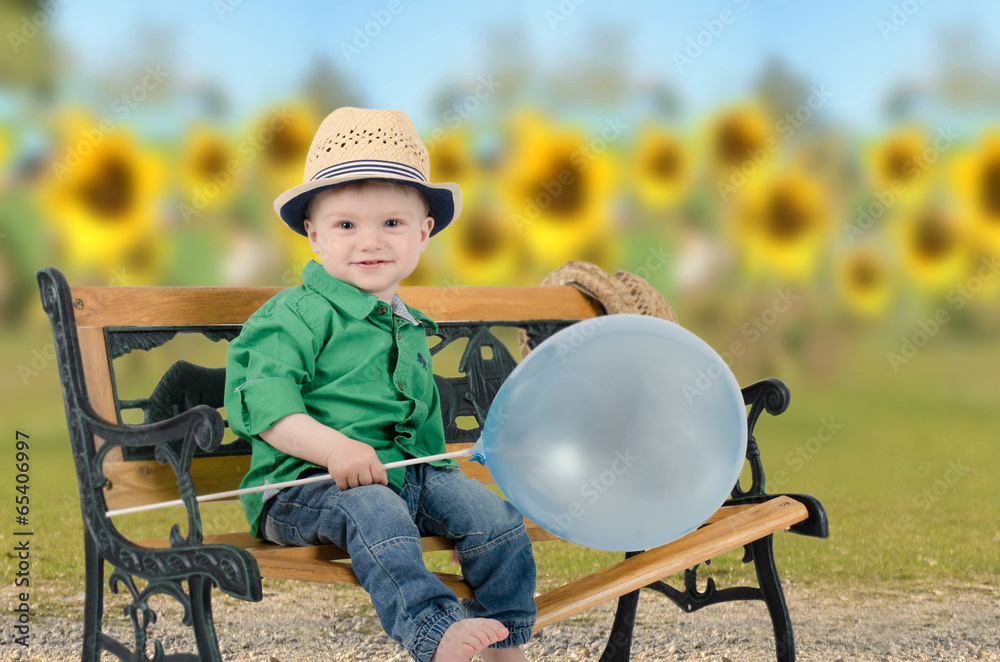 Junge mit Luftballon vor einem Sonnenblumenfeld - obrazy, fototapety, plakaty 