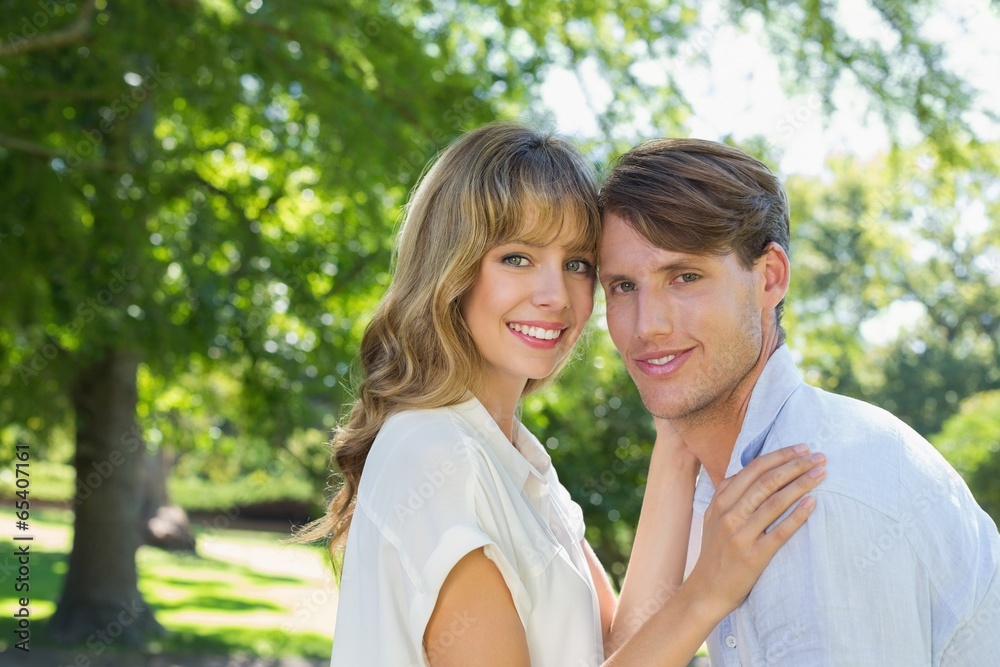 Cute couple hugging and smiling at camera in the park Cute couple hugging and smiling at camera in the park