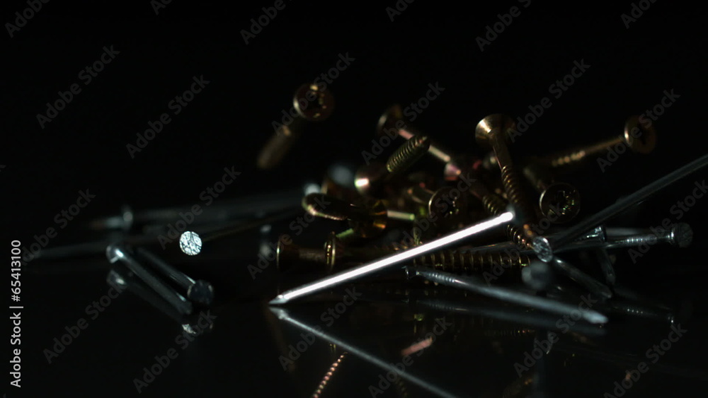 Nails and screws falling on black surface Nails and screws falling on black surface