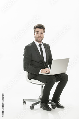 man in suit sitting with a laptop on his knees on isolated backg