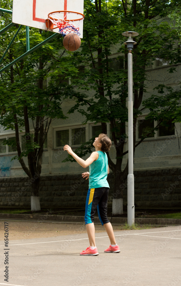 Young athletic teenage girl playing basketball