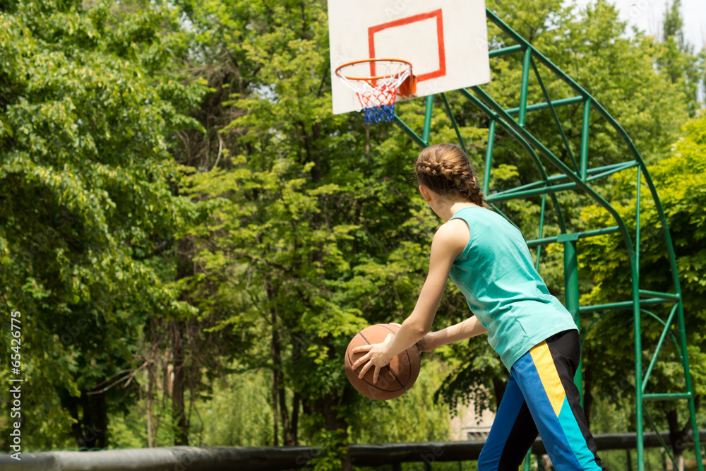 Sporty slender teenager playing basketball