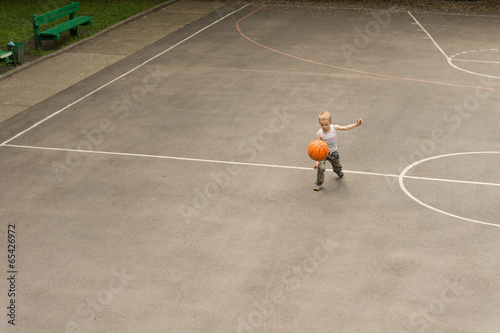 Small boy playing basketball bouncing the ball
