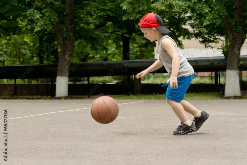 Small boy bouncing a basketball on a court