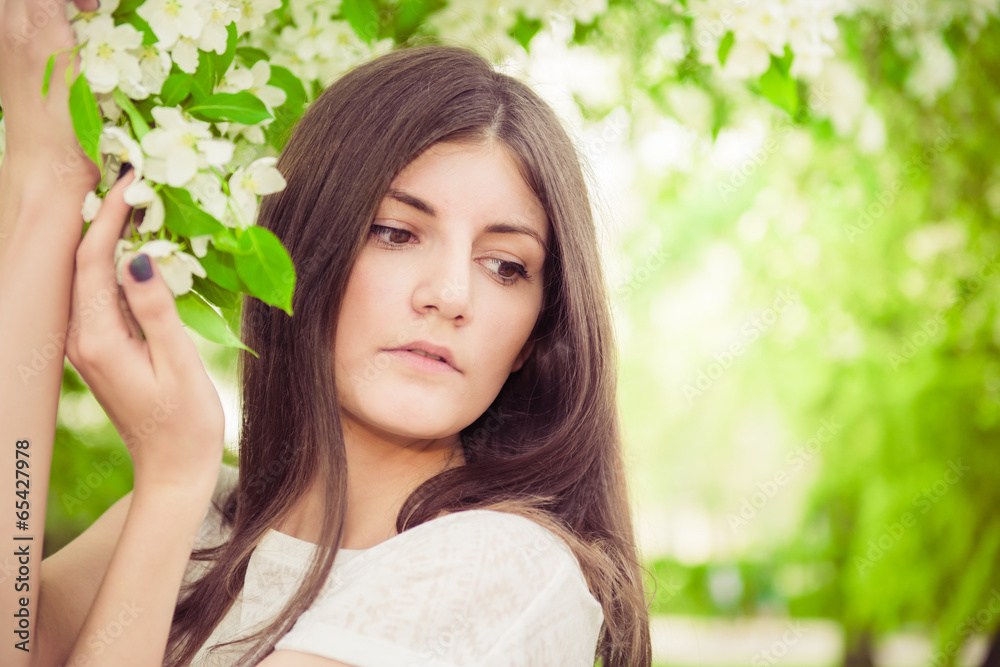 Beautiful spring brunette girl in blooming garden