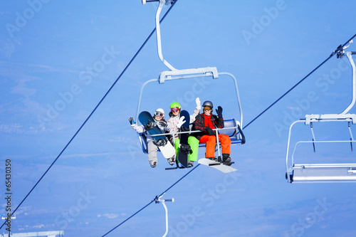 Three young people with snowboarders on ropeway
