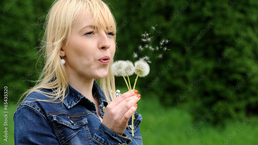 Beautiful young woman blowing a dandelion Beautiful young woman blowing a dandelion