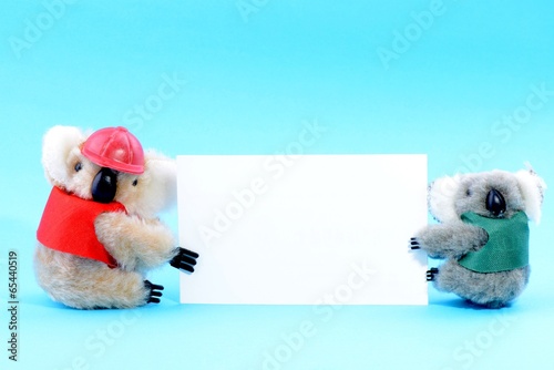 Two toy koala holding a blank white card © bbbar