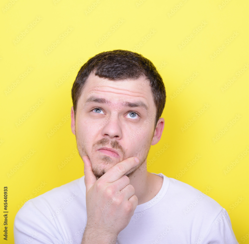 Portrait of man thinking and looking up against yellow backgroun