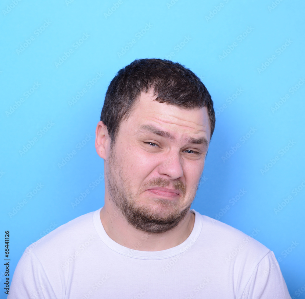 Portrait of man with dusgusted gesture against blue background Portrait of man with dusgusted gesture against blue background