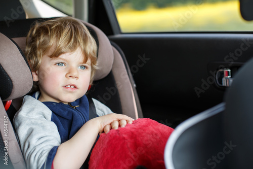 Portrait of little boy sitting in safety car seat