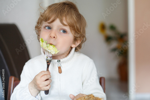 Little boy eating salad and bread at home, healthy eating for ki photo