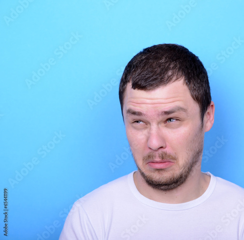 Portrait of man with dusgusted gesture against blue background