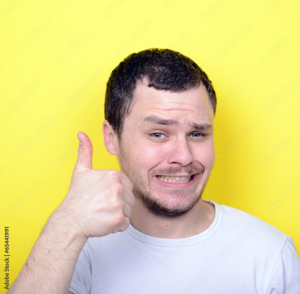 Portrait of with funny expression holding thumbs up against yell Portrait of with funny expression holding thumbs up against yell