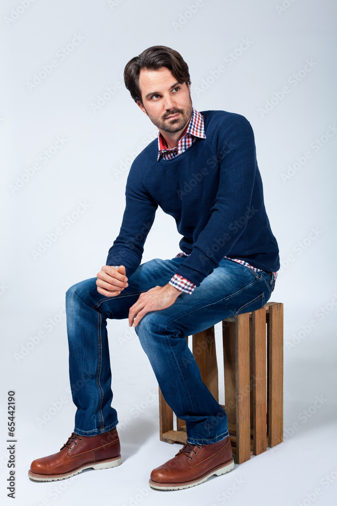 Handsome young man sitting on a wooden box Handsome young man sitting on a wooden box