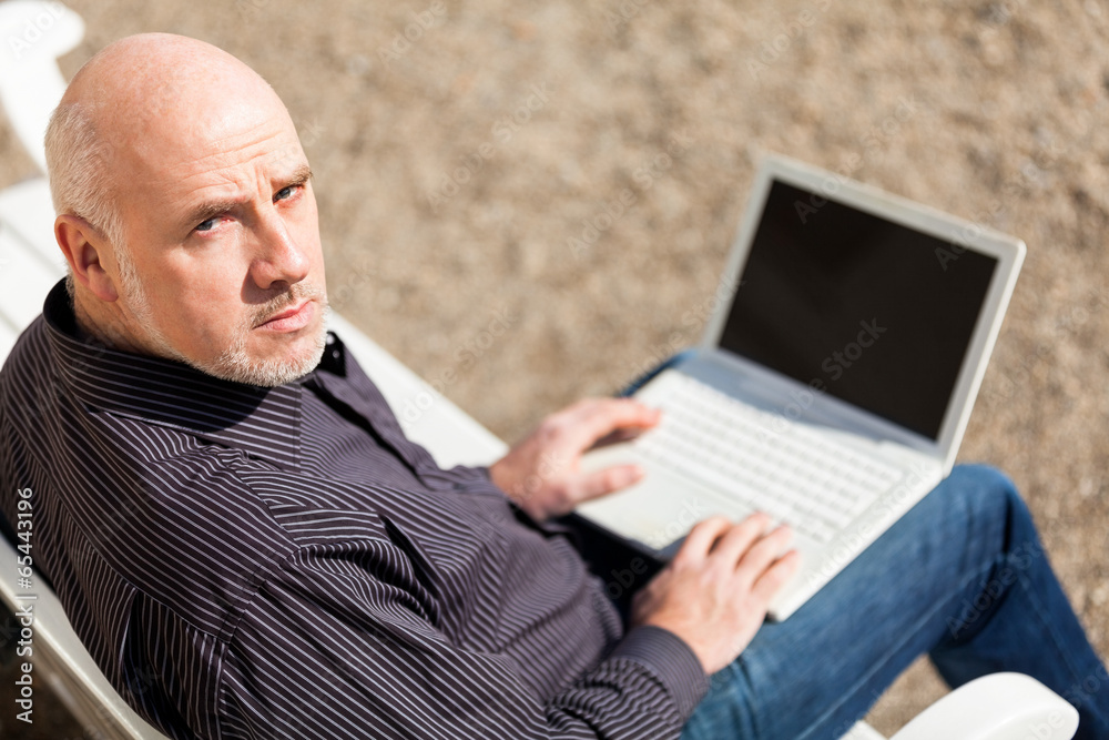 Man sitting on a bench using a laptop Man sitting on a bench using a laptop