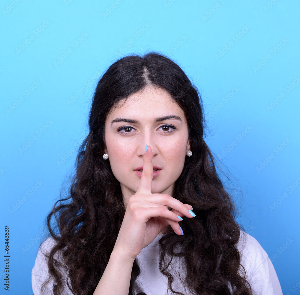 Portrait of girl with gesture for silence against blue backgroun Portrait of girl with gesture for silence against blue backgroun