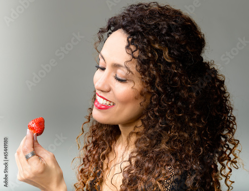 Attractive woman eating strawberry