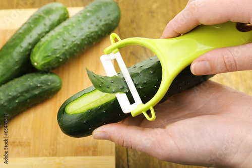 Hands peeling cucumber close up