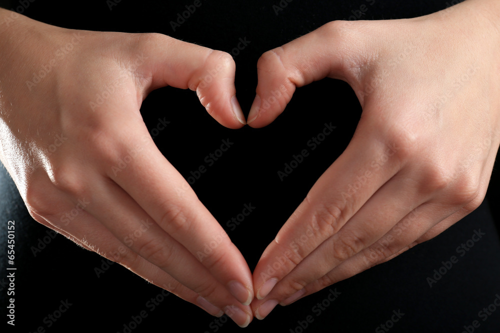 Obraz premium Human hands making heart on black background