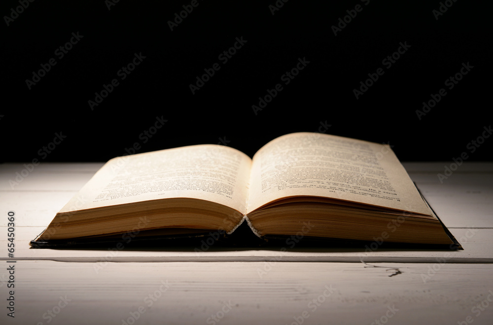 Old book on table on black background Old book on table on black background