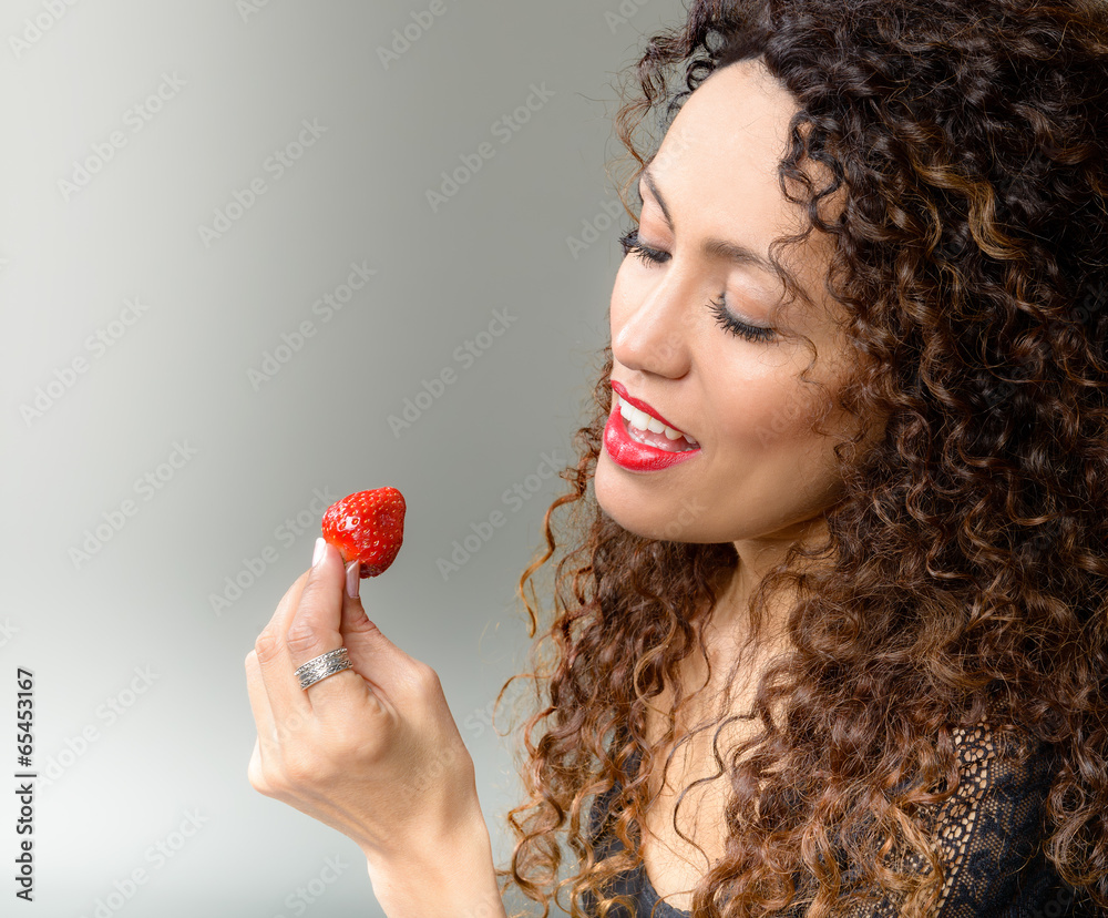 Attractive woman eating strawberry