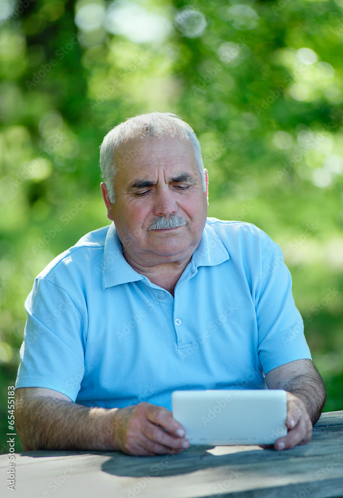 Elderly man reading on a tablet computer Elderly man reading on a tablet computer