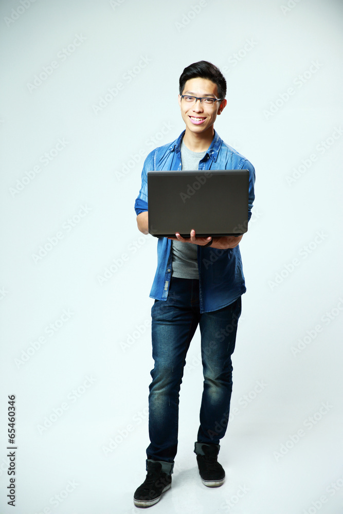 asian man standing with laptop on gray background asian man standing with laptop on gray background