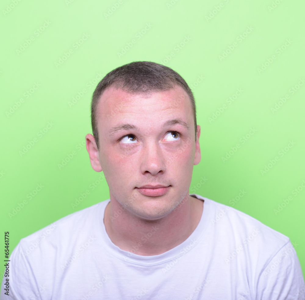 Fototapeta premium Portrait of man thinking and looking up against green background