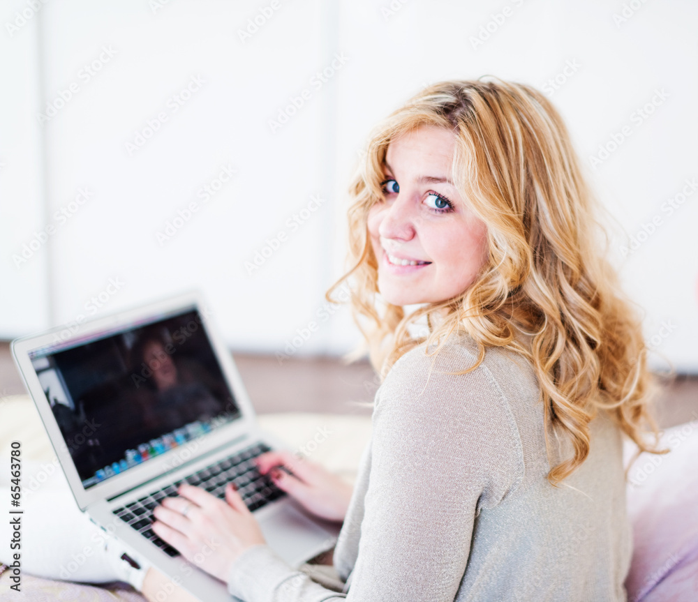 Fototapeta premium Portrait of beautiful young woman with laptop on bed