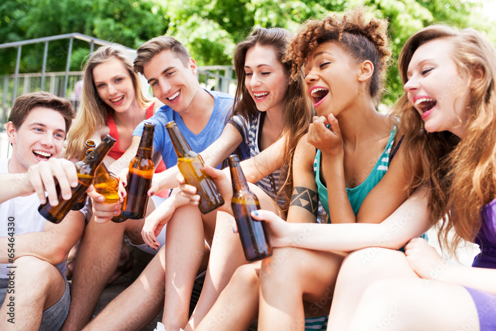 © pikselstock - Group of friends sitting with beers in their hands