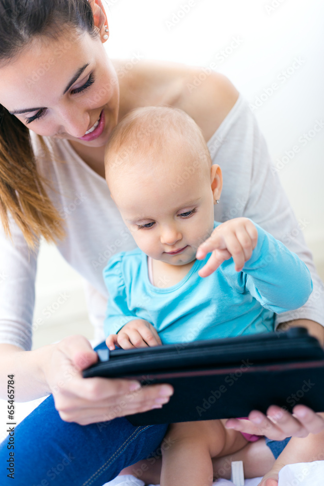 Mother and baby girl using digital tablet at home Mother and baby girl using digital tablet at home