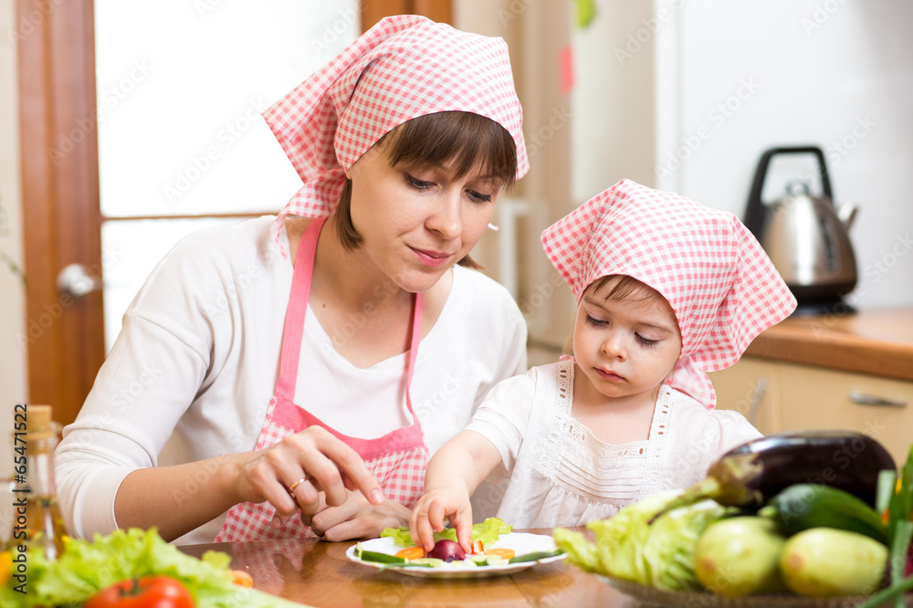 mother and kid girl making funny face from vegetables on plate mother and kid girl making funny face from vegetables on plate