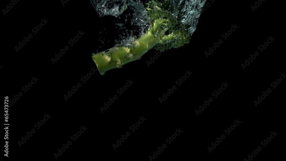Broccoli falling in water on black background