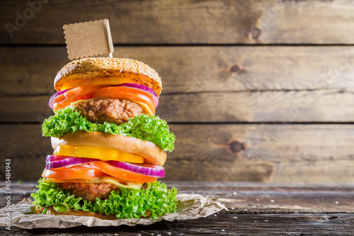 Double-decker burger on wooden background with space to menu