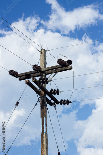 electrical post by the road with power line cables, against blue