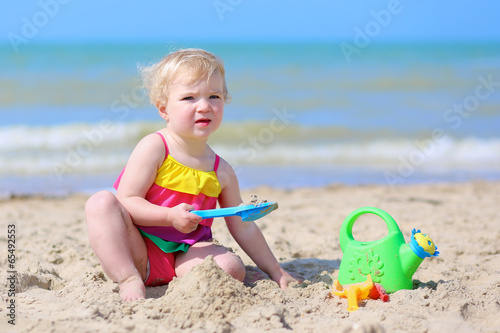 Happy little girl building sand castles on the beach